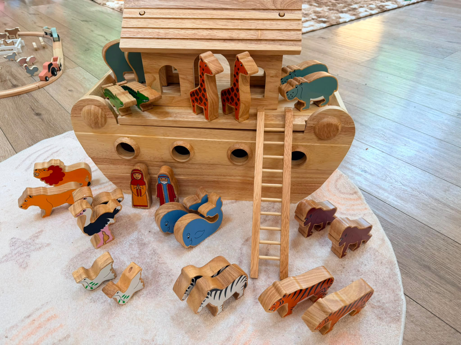 Wooden Noah's Ark toy with colourful hand-painted animals on a soft rug